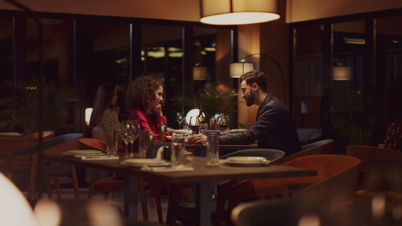 Couple at a candlelit restaurant, warm intimate lighting