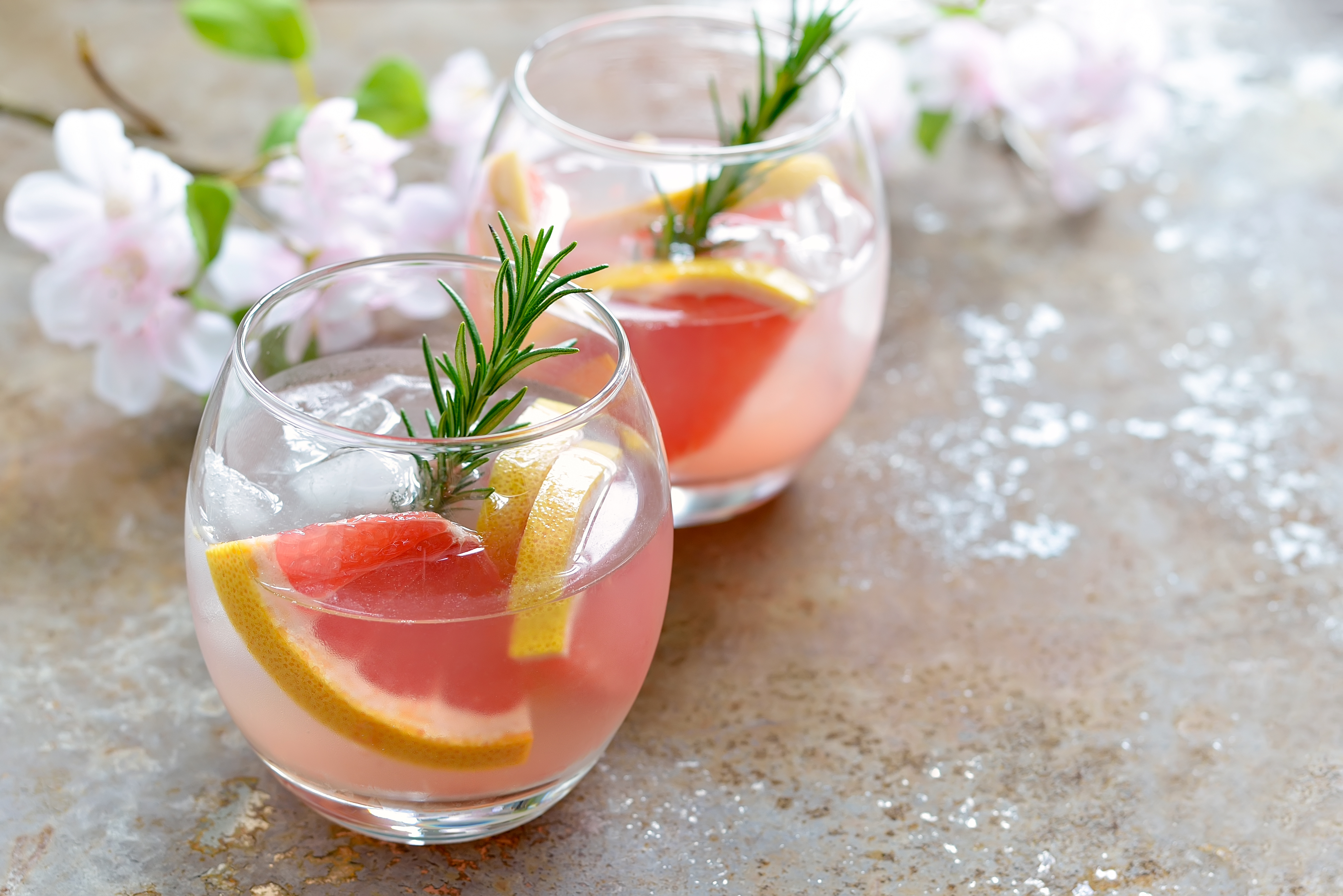 A pink grapefruit cocktail with rosemary over ice