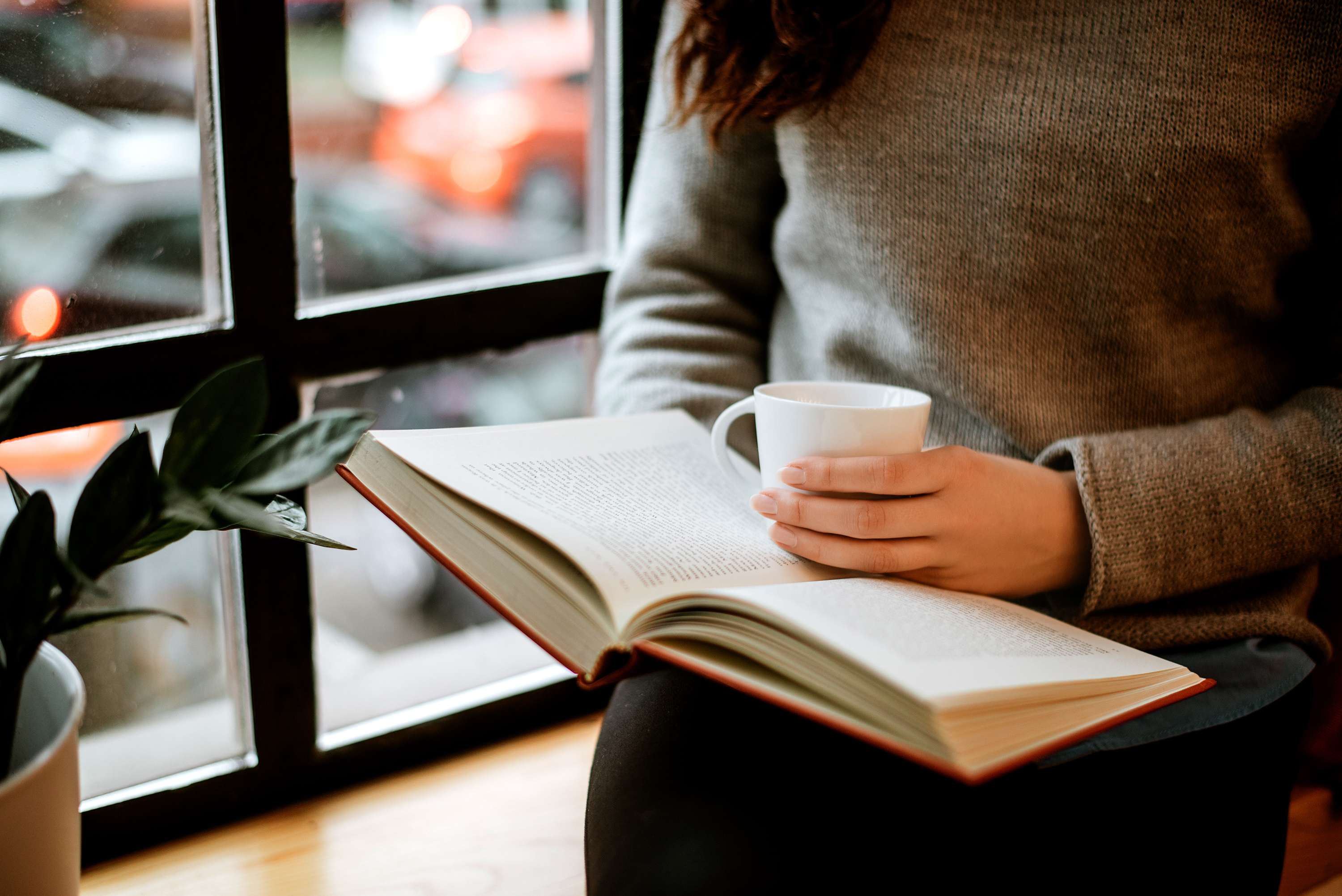 A person reading a book with coffee